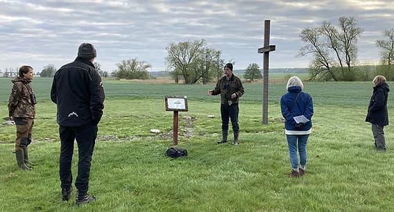 En grupp står vid ett stort träkors