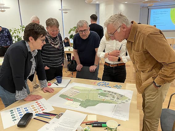 Fem deltagare står runt ett bord