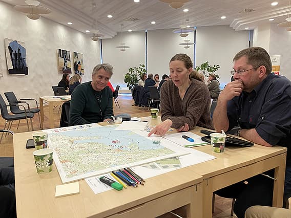 Tre deltagare sitter runt bordet