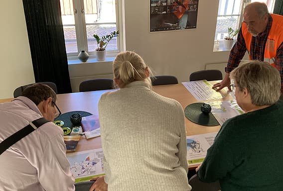 Fyra deltagare står runt ett bord och tittar på dokumentation