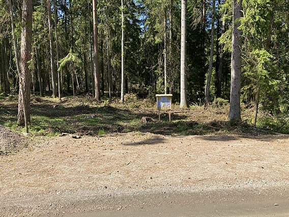Parkeringsplats med informationstavla i skogen