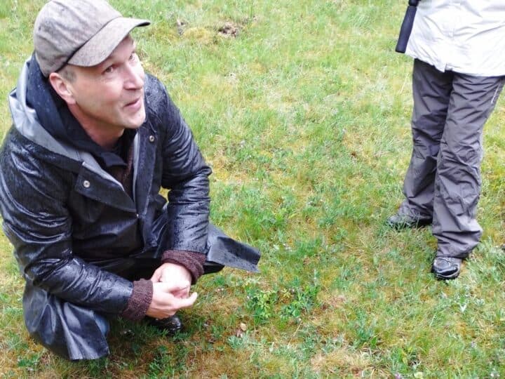 Ledaren sitter på huk och berättar för deltagare