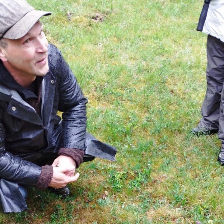 Ledaren sitter på huk och berättar för deltagare