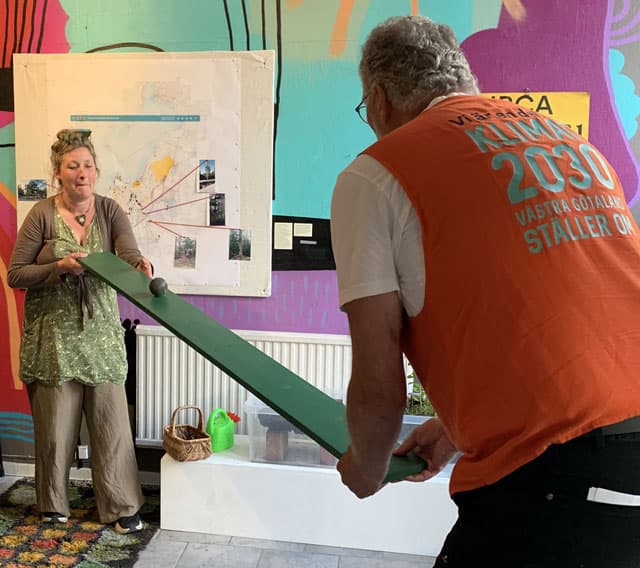 Anna rullar en boll på en bräda till Jan