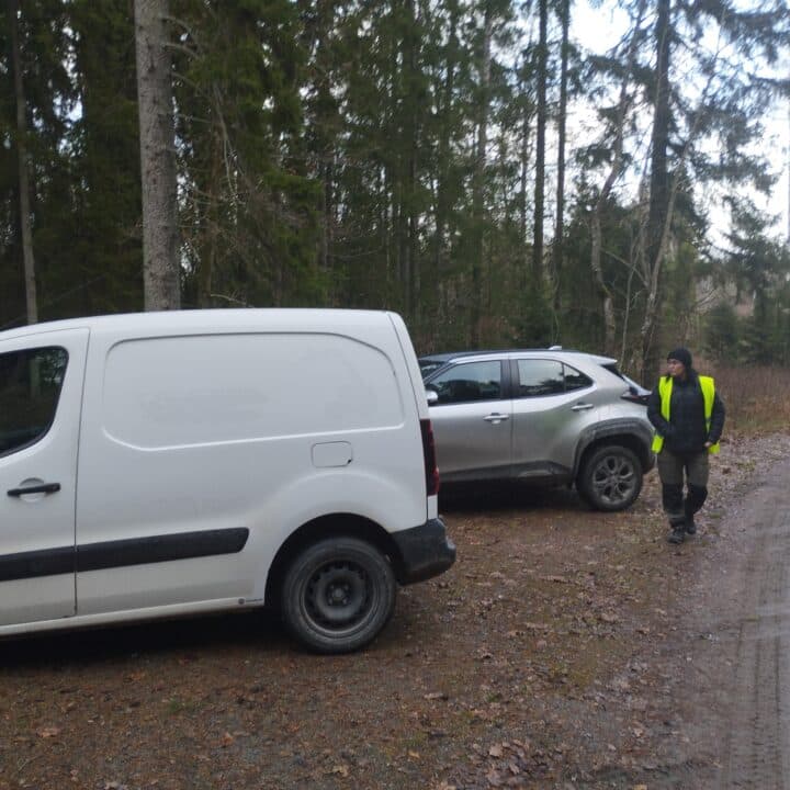 Bilar står på parkeringen och ledaren kommer gående
