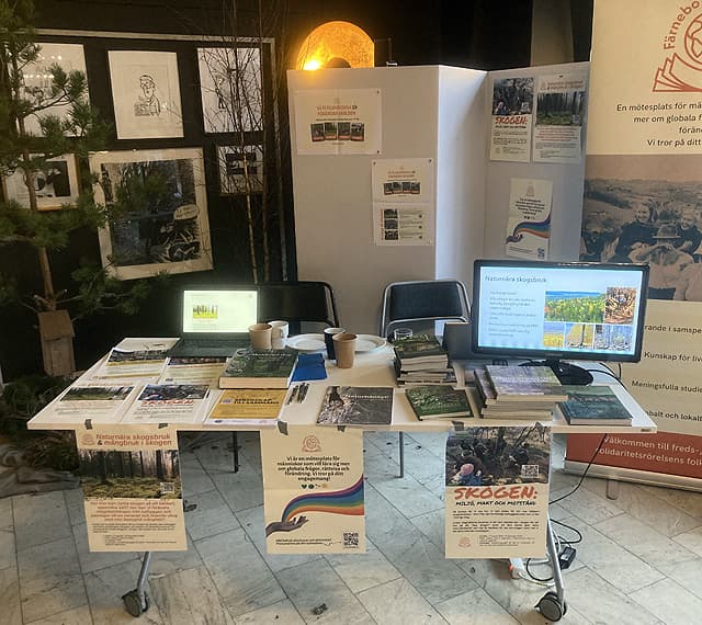 Ett bord med två datorskärmar, böcker och informationsblad.