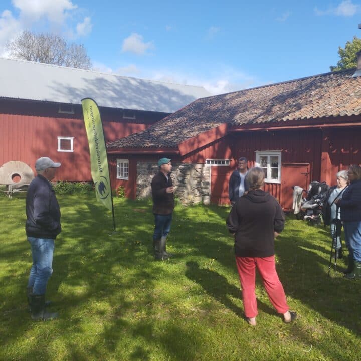 Personer utomhus framför hembygdsgård.
